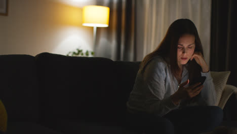 Mujer-Sentada-En-Un-Sofá-En-Casa-Viendo-Una-Película-O-Programa-O-Navegando-Por-Internet-En-Un-Teléfono-Móvil-16